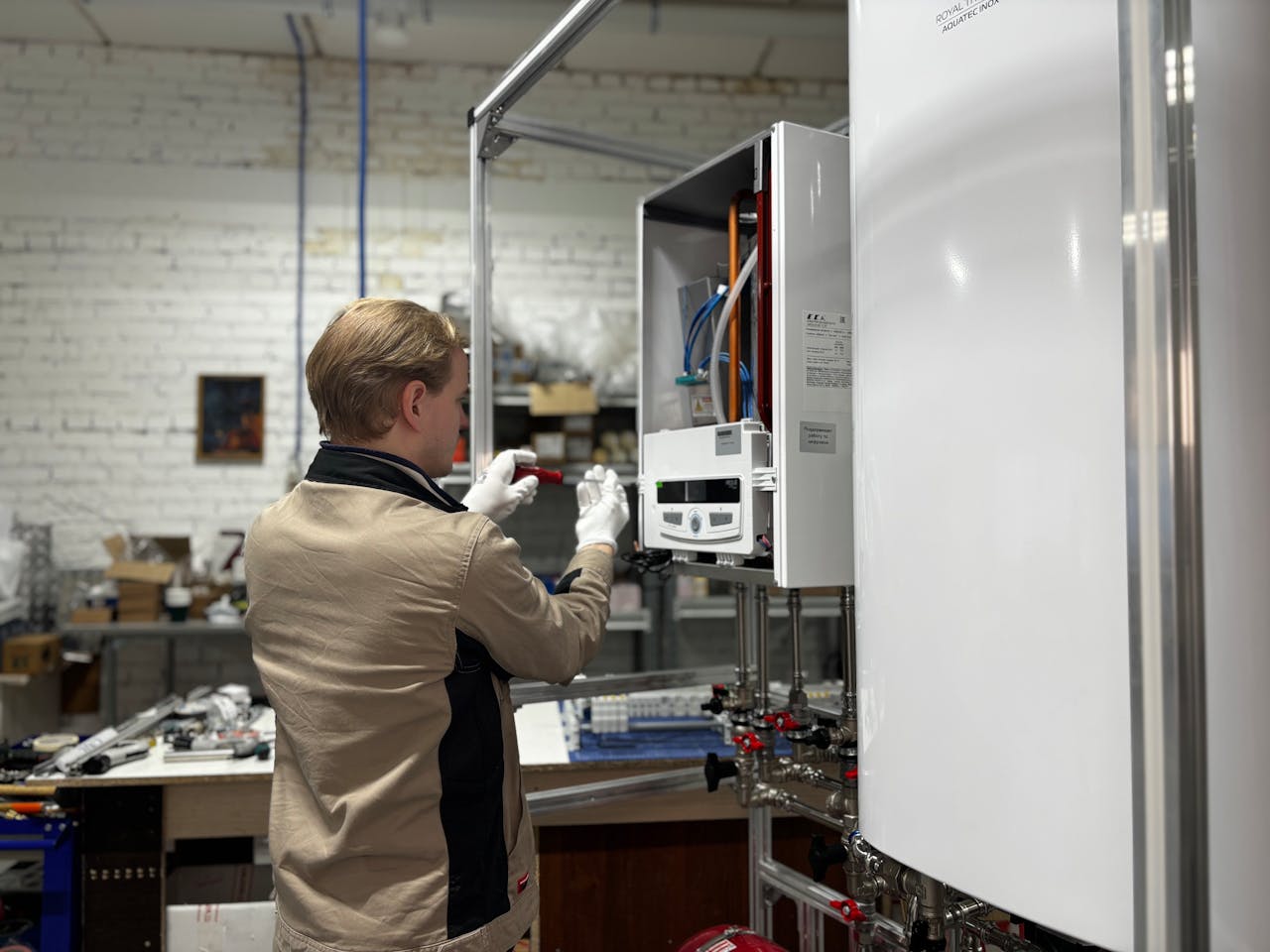 About Technician inspects and repairs a heating system in an industrial workshop setting.