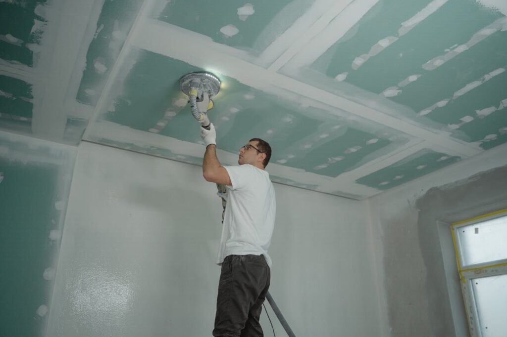 pexels photo 6474129 A worker expertly polishes a ceiling indoors, demonstrating home renovation skills.